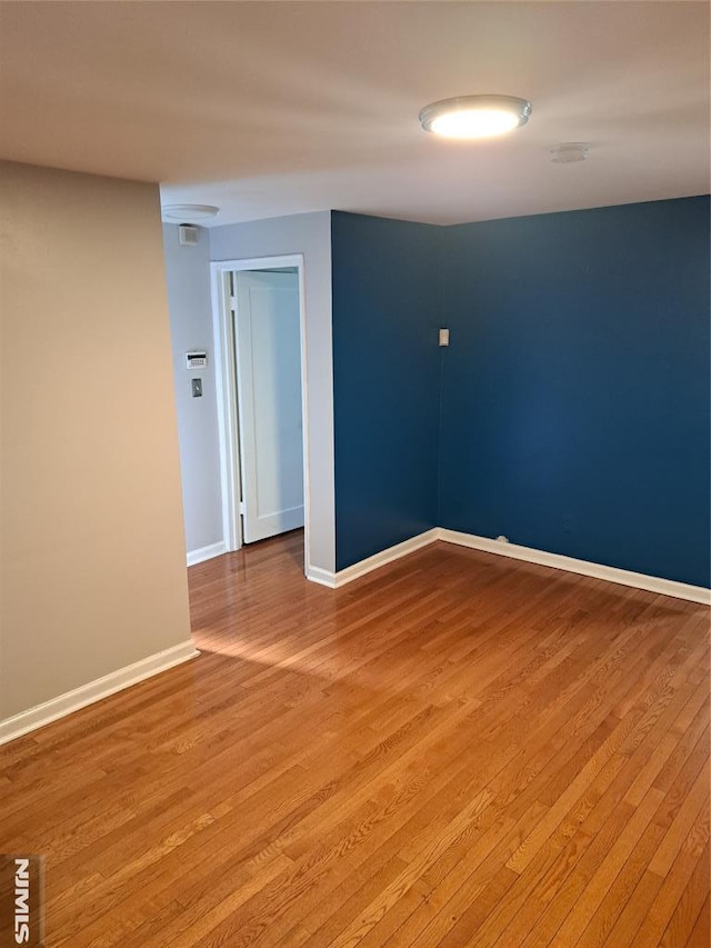 spare room featuring baseboards and light wood-type flooring