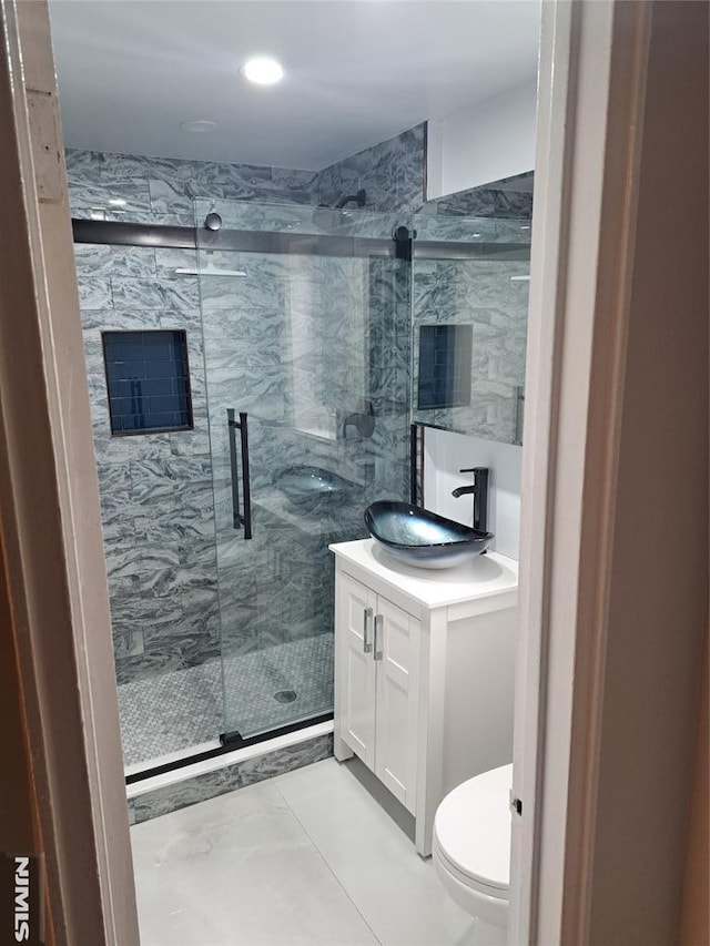 bathroom featuring vanity, toilet, and a marble finish shower