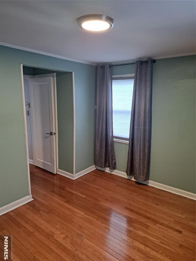 spare room with hardwood / wood-style flooring, crown molding, and baseboards