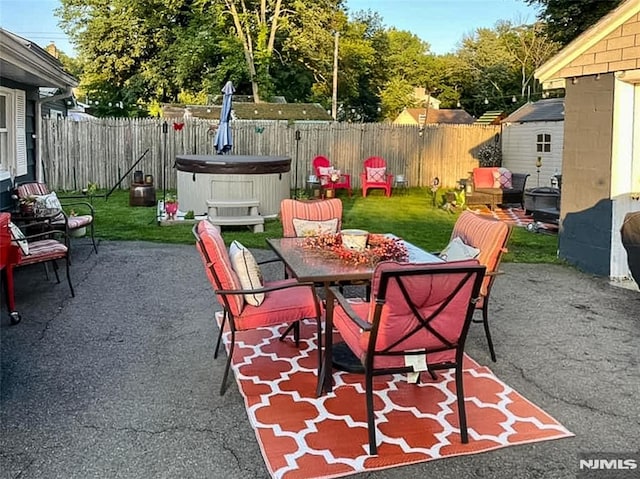 view of patio featuring outdoor dining space, an outdoor structure, a fenced backyard, and a hot tub