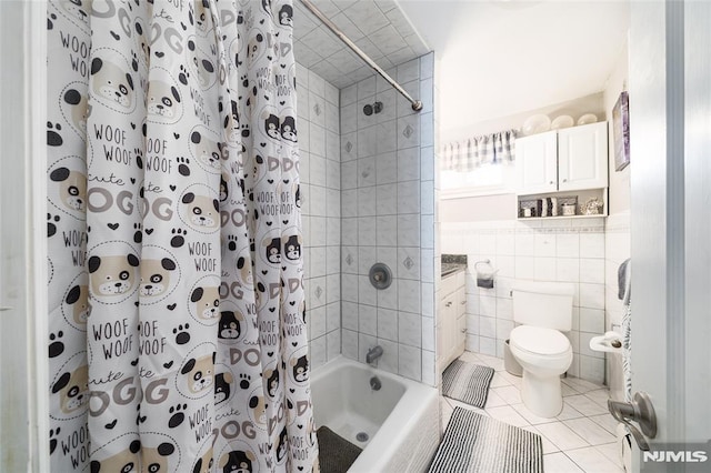 full bathroom featuring tile patterned flooring, toilet, wainscoting, shower / bath combination with curtain, and tile walls