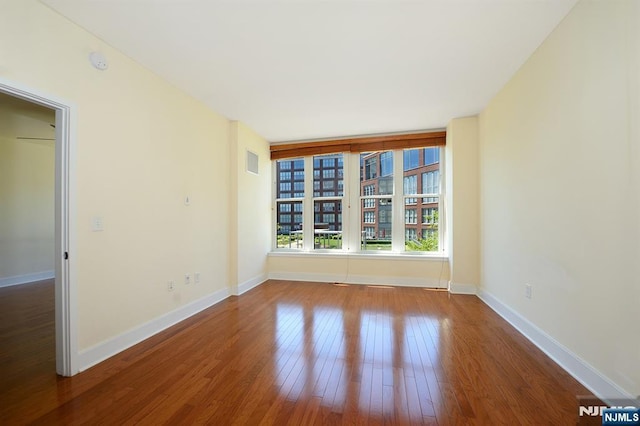 unfurnished room featuring visible vents, baseboards, and hardwood / wood-style flooring