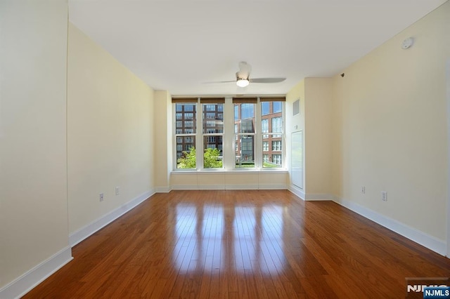 empty room featuring a ceiling fan, wood finished floors, and baseboards