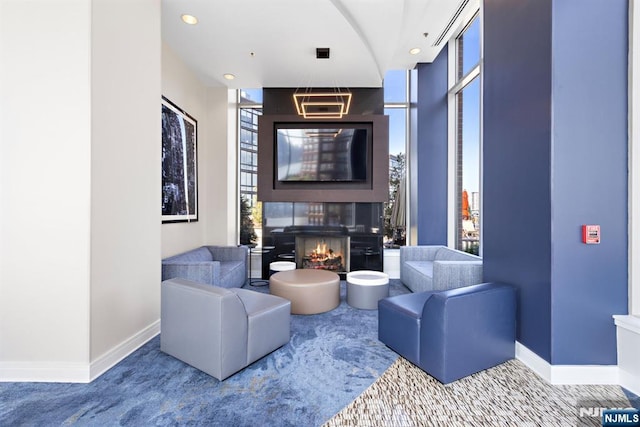 living room with a large fireplace, recessed lighting, a wall of windows, and baseboards