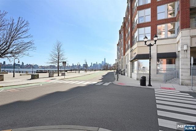 view of road featuring street lights, curbs, and sidewalks