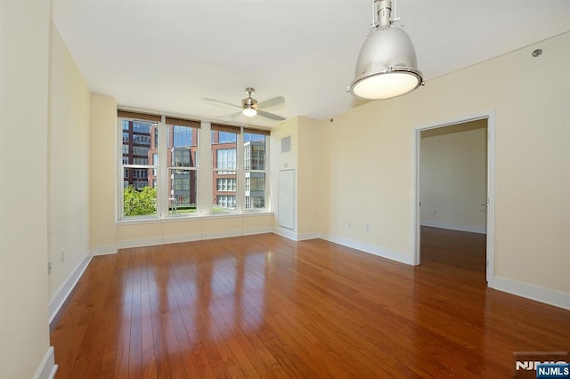 spare room with baseboards, hardwood / wood-style floors, and a ceiling fan