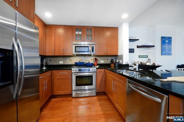 kitchen featuring light wood finished floors, brown cabinets, appliances with stainless steel finishes, and a sink