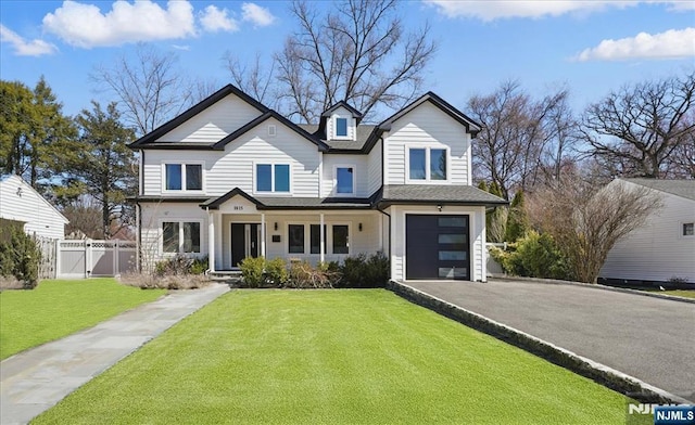 view of front facade featuring fence, an attached garage, aphalt driveway, a front lawn, and a gate