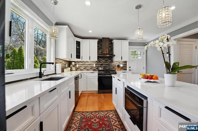 kitchen with built in microwave, a sink, gas range, wall chimney exhaust hood, and tasteful backsplash