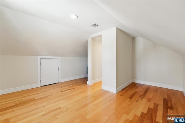 bonus room with lofted ceiling, baseboards, light wood-type flooring, and visible vents