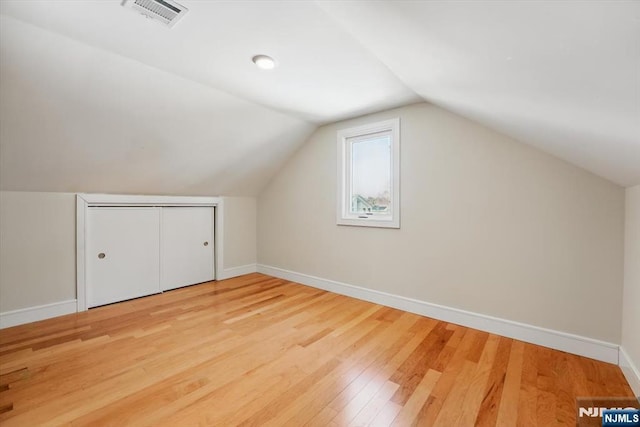 additional living space featuring vaulted ceiling, baseboards, visible vents, and light wood-style floors