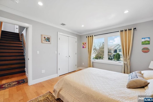bedroom featuring a closet, ornamental molding, recessed lighting, light wood-style flooring, and baseboards