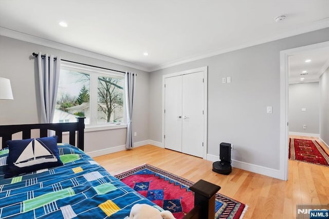 bedroom with baseboards, ornamental molding, a closet, and wood finished floors