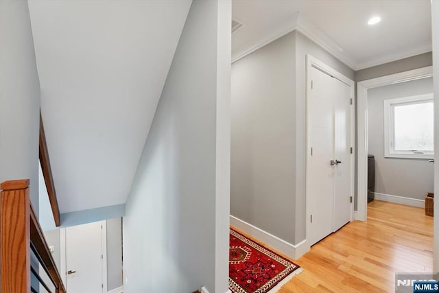 corridor featuring light wood-style flooring, baseboards, ornamental molding, and recessed lighting