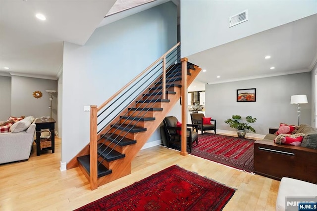 stairway with wood finished floors, ornamental molding, visible vents, recessed lighting, and baseboards