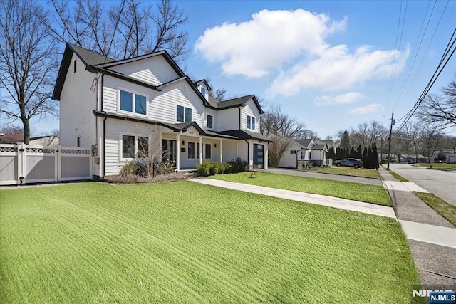 view of front of home with a gate, fence, a front lawn, and driveway