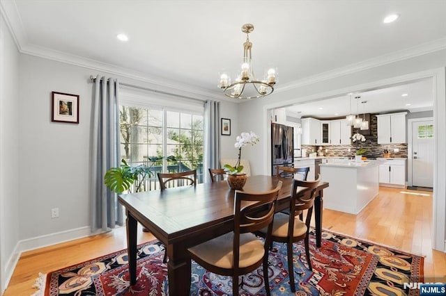 dining area with ornamental molding, light wood finished floors, a chandelier, and recessed lighting
