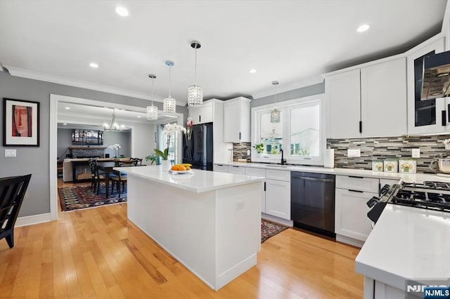 kitchen featuring freestanding refrigerator, light countertops, stainless steel dishwasher, and a notable chandelier