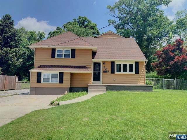 tri-level home featuring a front yard and fence