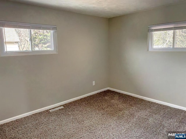 spare room featuring visible vents, baseboards, and carpet flooring