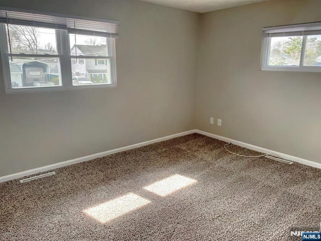 unfurnished room featuring visible vents, baseboards, and carpet