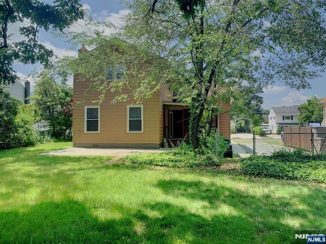 rear view of property with a lawn, a chimney, and fence