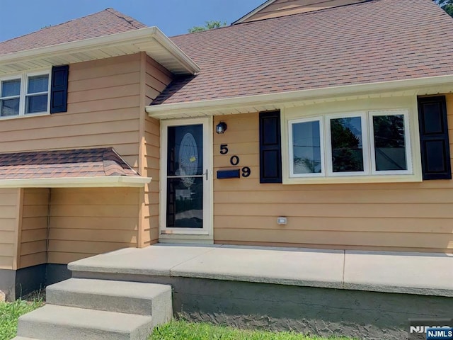 doorway to property featuring roof with shingles