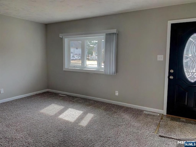 foyer with visible vents, carpet, and baseboards