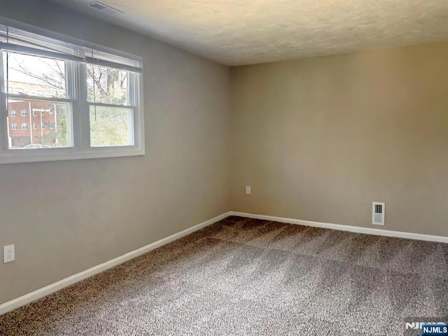 spare room with visible vents, carpet, and baseboards