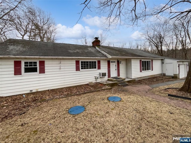 ranch-style home with an AC wall unit and a chimney