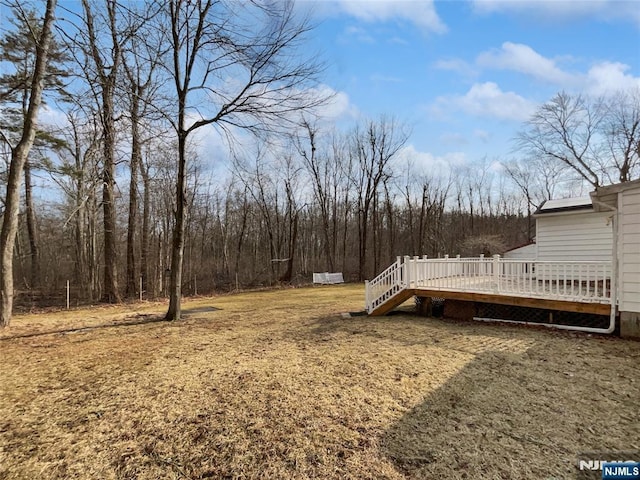 view of yard featuring a wooded view and a deck