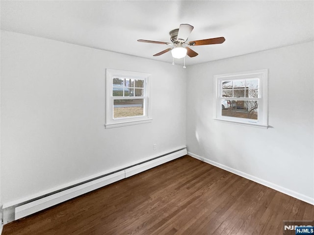 spare room featuring a baseboard heating unit, dark wood-style floors, baseboards, and a ceiling fan