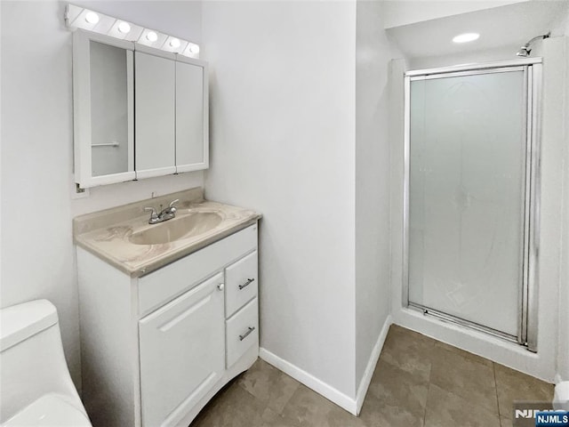 bathroom featuring vanity, toilet, baseboards, and a stall shower