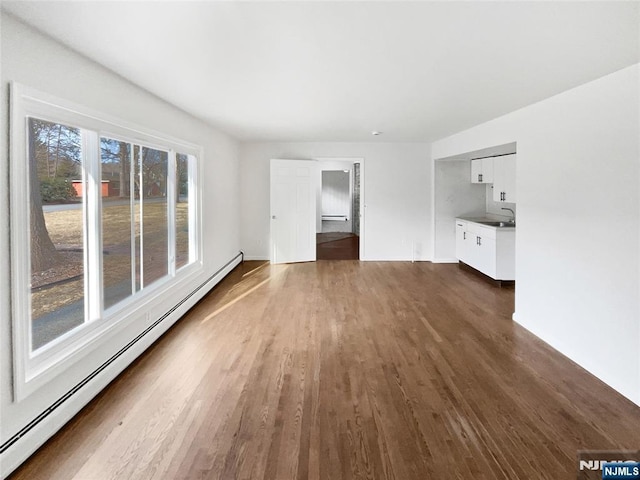 unfurnished living room with dark wood finished floors, a sink, and a baseboard radiator