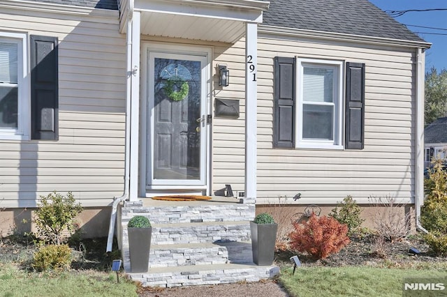 view of exterior entry featuring roof with shingles