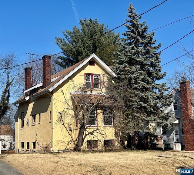 view of property exterior featuring a yard, a chimney, and stucco siding