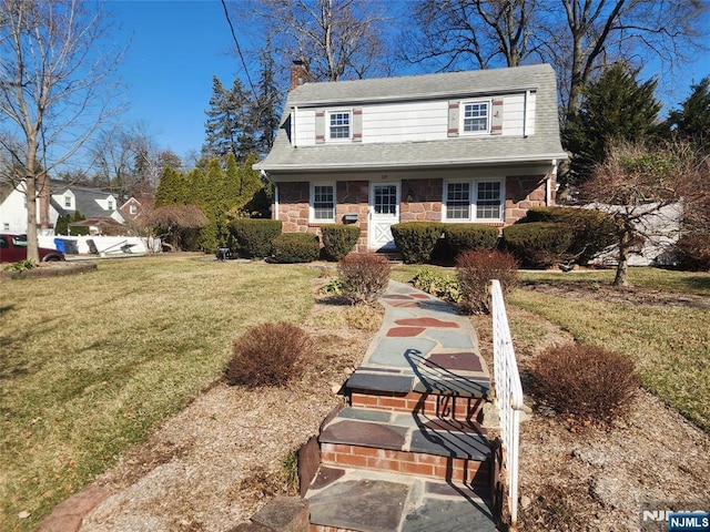 view of front of house with a front yard, stone siding, and a chimney