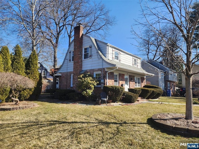 view of front of house with stone siding, a gambrel roof, a chimney, and a front yard