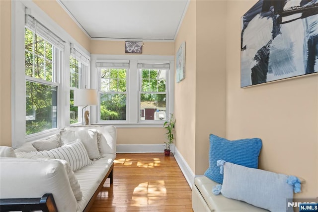 sunroom / solarium featuring crown molding, baseboards, wood-type flooring, and a wealth of natural light