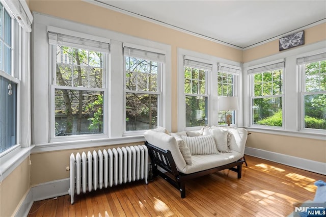 sunroom / solarium with baseboards, ornamental molding, radiator heating unit, and hardwood / wood-style floors
