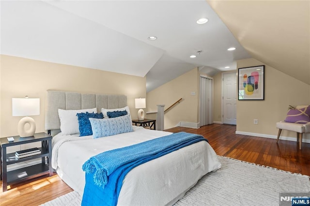 bedroom featuring baseboards, wood finished floors, and lofted ceiling