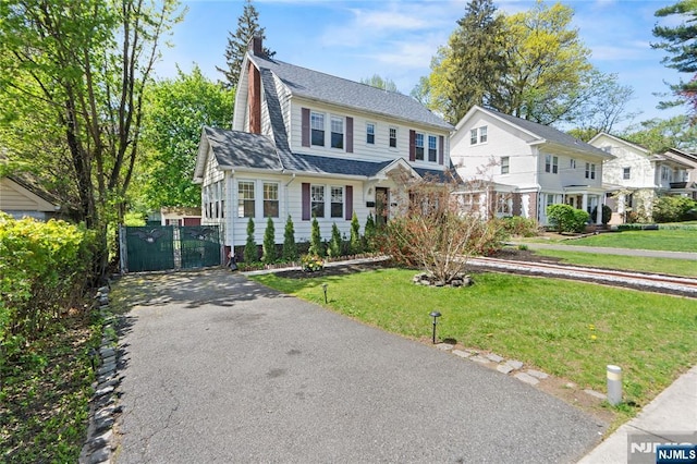 view of front facade with a chimney, a gate, and a front lawn