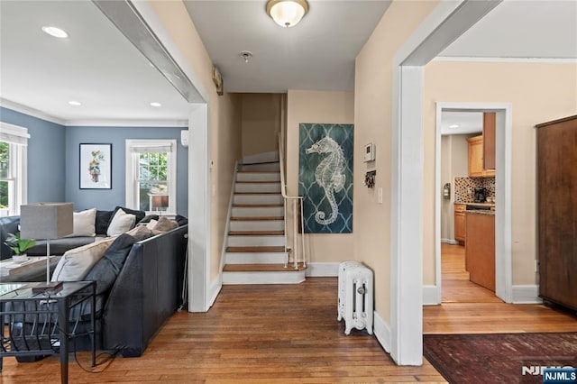 interior space featuring radiator heating unit, ornamental molding, plenty of natural light, and light wood finished floors