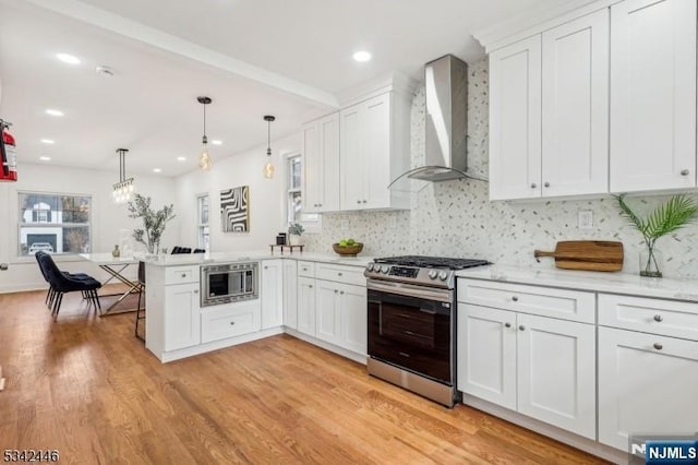 kitchen with white cabinetry, a peninsula, wall chimney exhaust hood, and stainless steel appliances