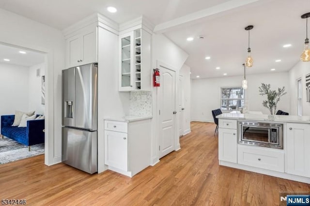 kitchen featuring light wood finished floors, glass insert cabinets, light countertops, white cabinets, and stainless steel appliances