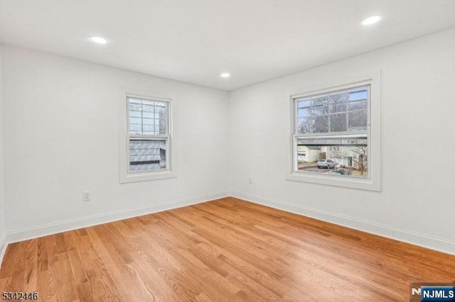 empty room featuring recessed lighting, baseboards, and light wood-style floors