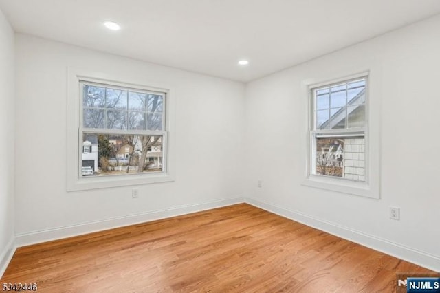 unfurnished room featuring baseboards, plenty of natural light, and wood finished floors