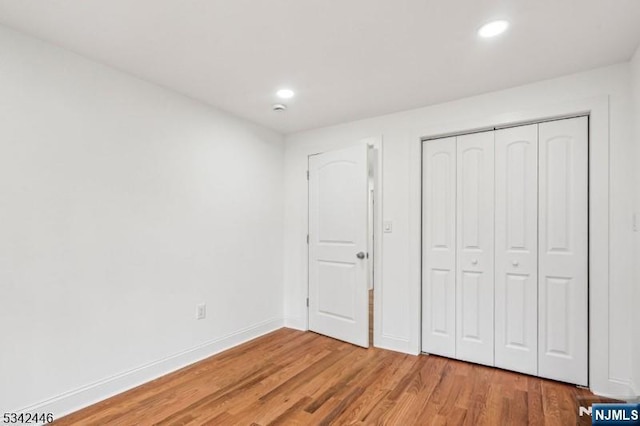 unfurnished bedroom with recessed lighting, a closet, baseboards, and light wood-style flooring