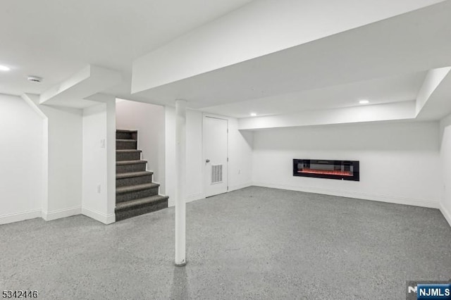 finished basement featuring a glass covered fireplace, stairway, recessed lighting, and baseboards