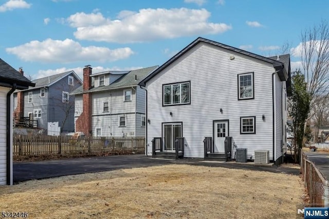 back of house with entry steps, central AC, and fence